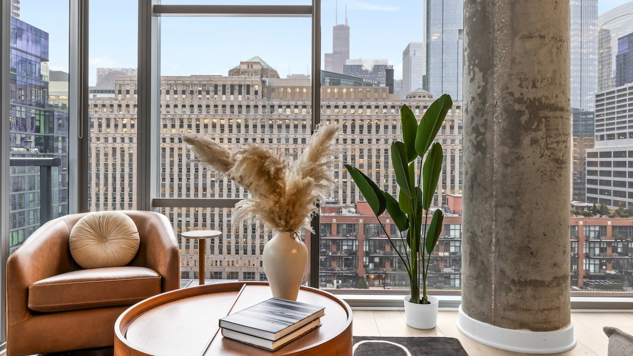 Cozy living area at 3Eleven Luxury Apartments in Chicago with leather chair, modern decor, and floor-to-ceiling windows