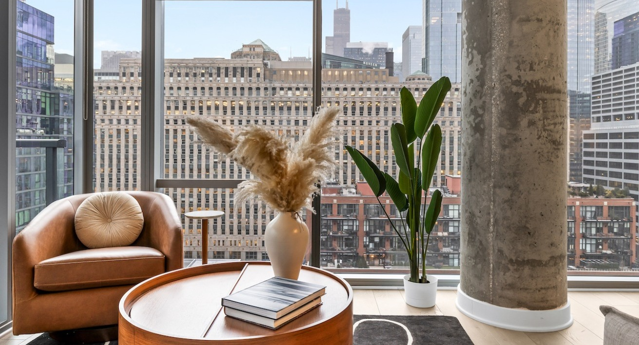 Cozy living area at 3Eleven Luxury Apartments in Chicago with leather chair, modern decor, and floor-to-ceiling windows