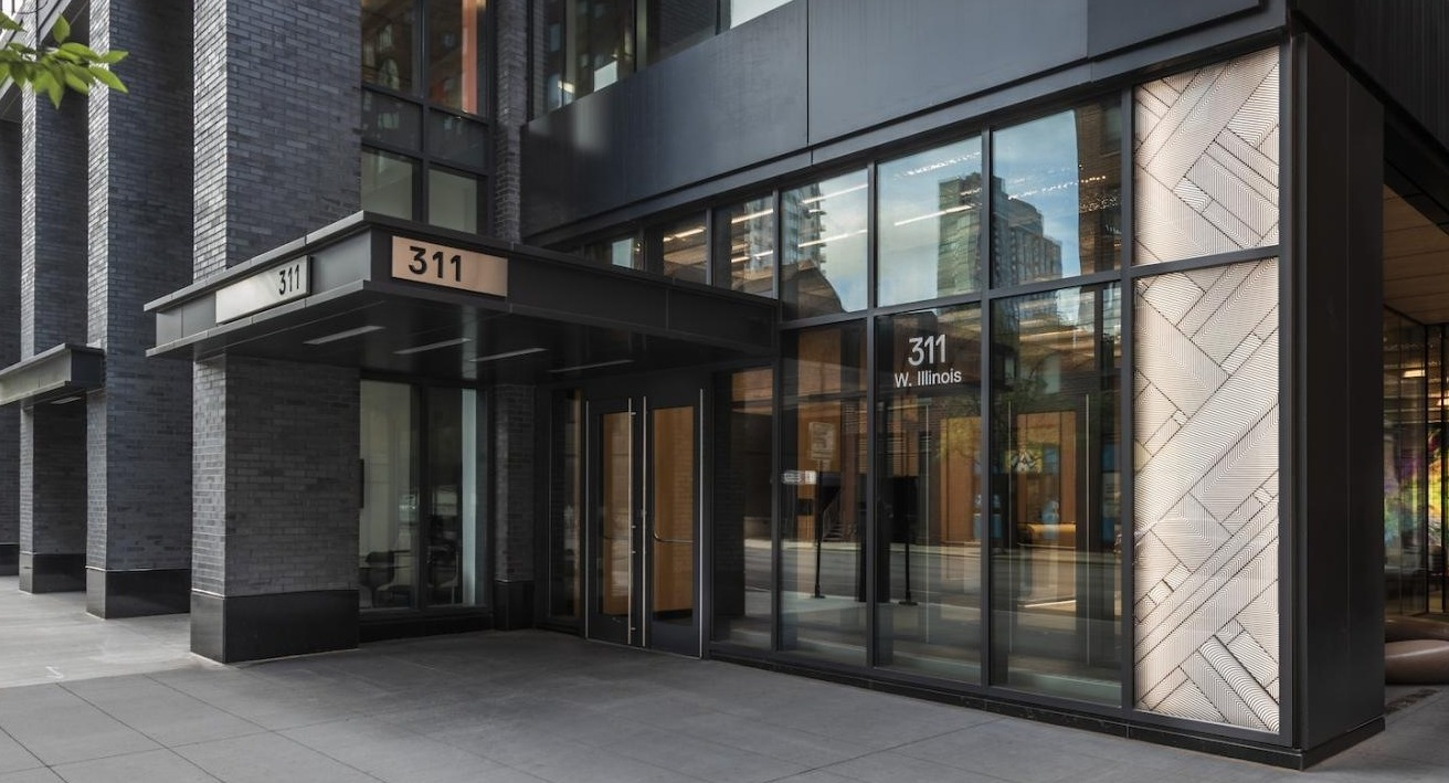 Street-level entrance of 3Eleven Luxury Apartments in Chicago with sleek black exterior, large glass windows, and modern lobby design