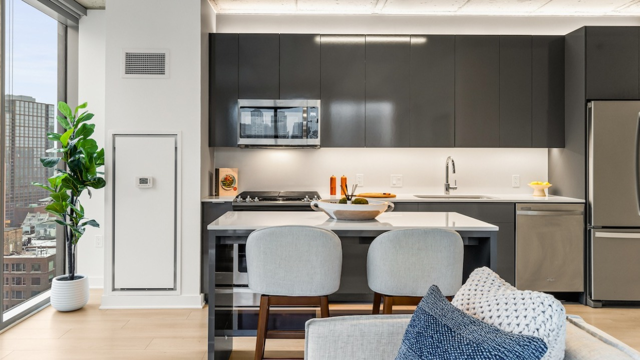 Contemporary kitchen at 3Eleven Luxury Apartments in Chicago with stainless steel appliances, island seating, and city views
