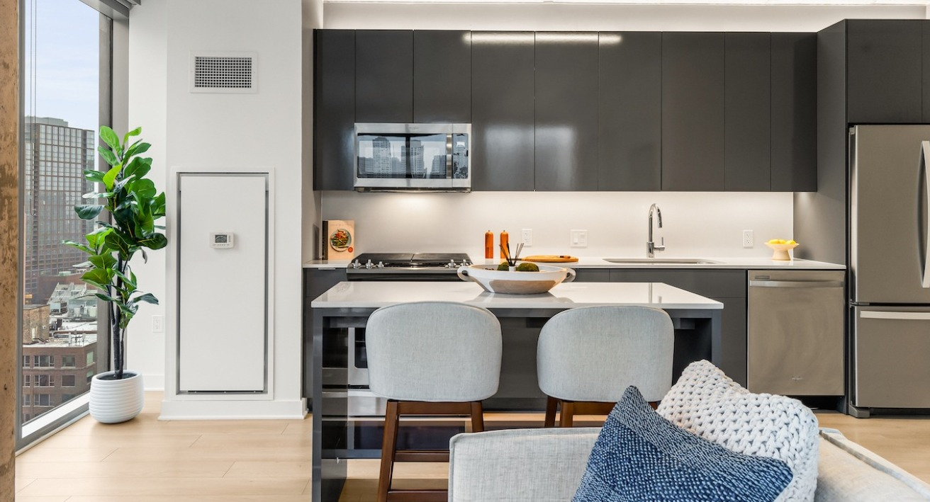Contemporary kitchen at 3Eleven Luxury Apartments in Chicago with stainless steel appliances, island seating, and city views