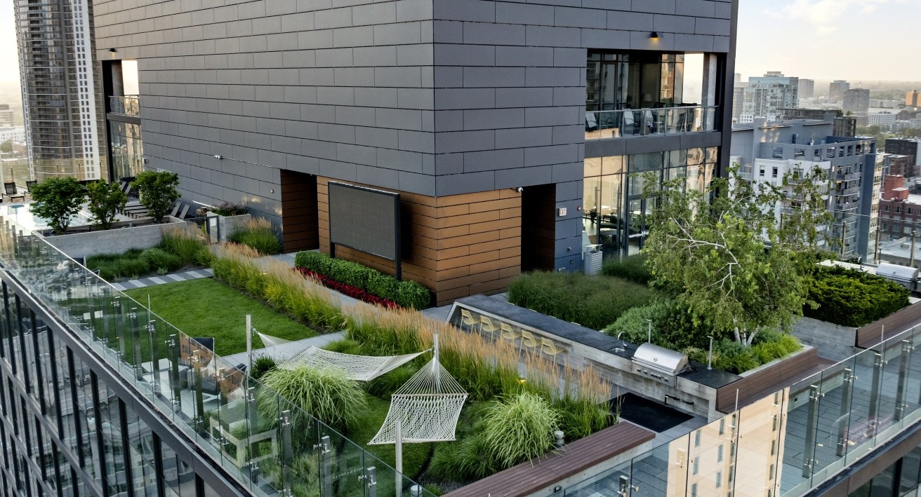Rooftop garden at 3Eleven Luxury Apartments in Chicago featuring hammocks, lounge areas, outdoor grill, and landscaped greenery with skyline views