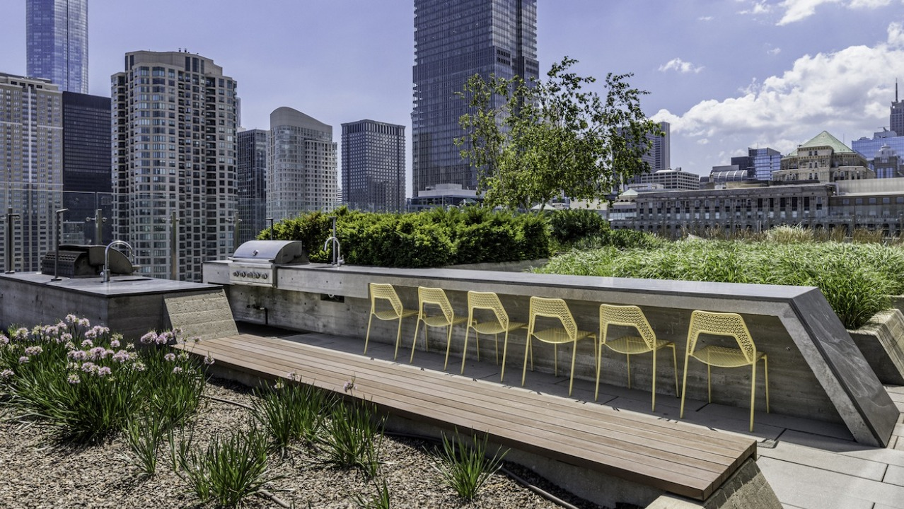 Rooftop grilling and dining area at 3Eleven Luxury Apartments in Chicago with outdoor seating, BBQ stations, and city skyline backdrop