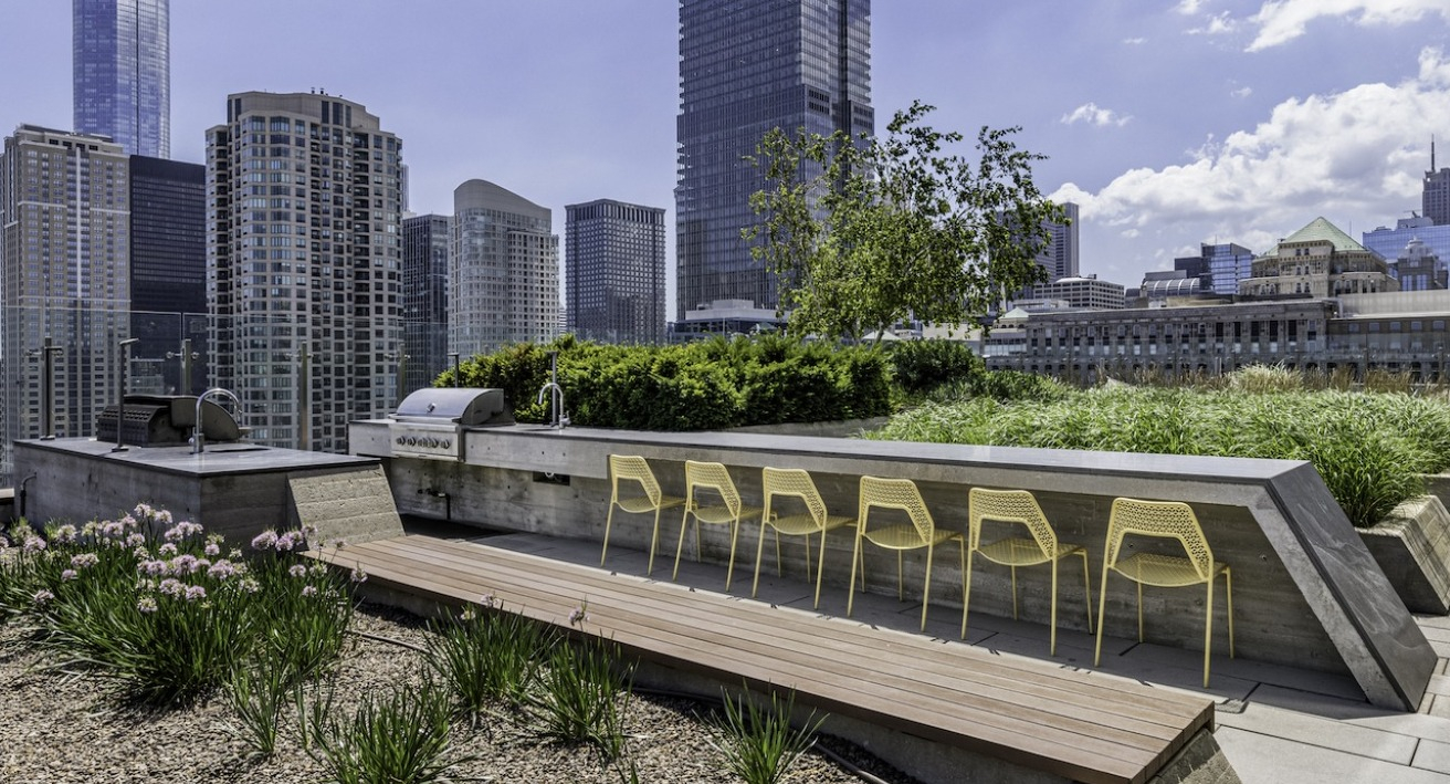 Rooftop grilling and dining area at 3Eleven Luxury Apartments in Chicago with outdoor seating, BBQ stations, and city skyline backdrop