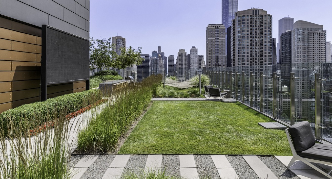 Rooftop lawn and lounge space at 3Eleven Luxury Apartments in Chicago featuring hammocks, grass seating area, and skyline views