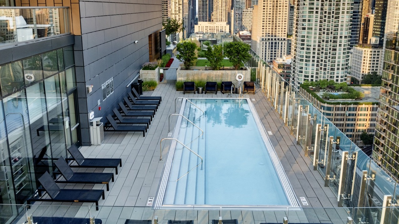 Rooftop pool at 3Eleven Luxury Apartments in Chicago with lounge chairs, glass railings, and sweeping views of the downtown skyline