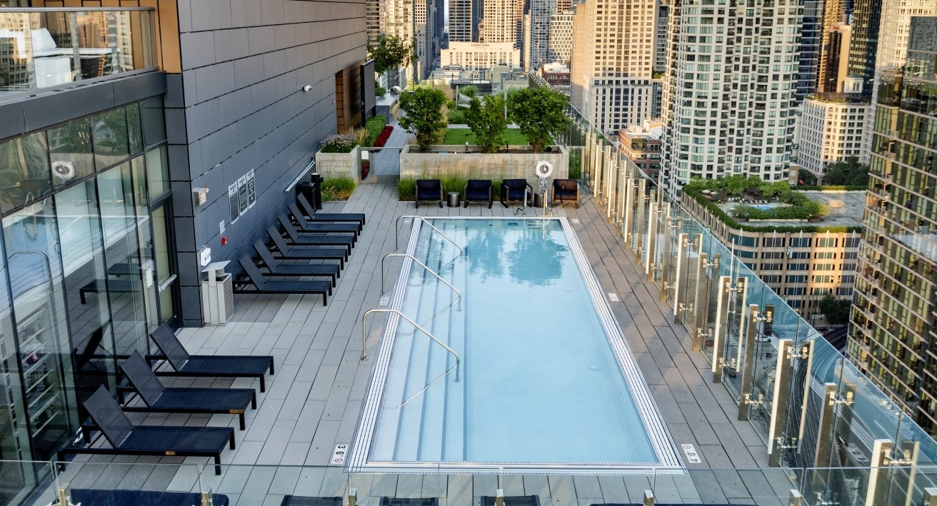 Rooftop pool at 3Eleven Luxury Apartments in Chicago with lounge chairs, glass railings, and sweeping views of the downtown skyline