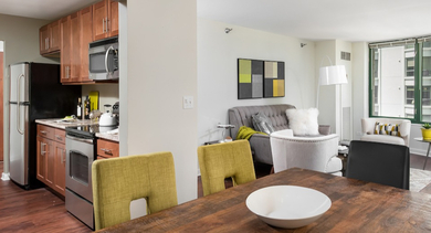 Cozy living and dining space with wood dining table, upholstered chairs, and large windows at 420 East Ohio apartments in Chicago