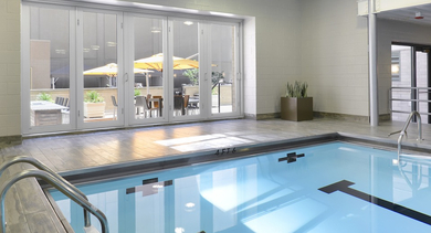 Indoor pool with glass doors opening to outdoor terrace and seating at 420 East Ohio apartments in Chicago, offering both indoor and outdoor relaxation