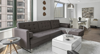 Bright living and dining area featuring a sectional sofa, glossy white coffee table, large windows, and adjacent dining set at 420 East Ohio apartments in Chicago