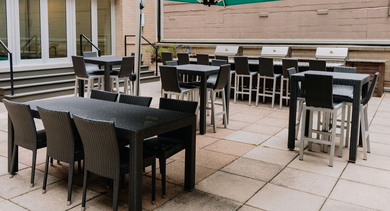 Outdoor grilling area with shaded tables, bar seating, and built-in BBQ stations at 420 East Ohio apartments in Chicago, perfect for summer dining