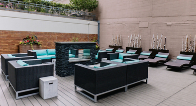 Outdoor terrace with lounge seating, turquoise cushions, and a modern fireplace at 420 East Ohio apartments in Chicago, perfect for relaxing and entertaining