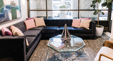 Resident lounge with sectional sofa, accent pillows, and a glass coffee table at 420 East Ohio apartments in Chicago, creating a stylish and inviting atmosphere