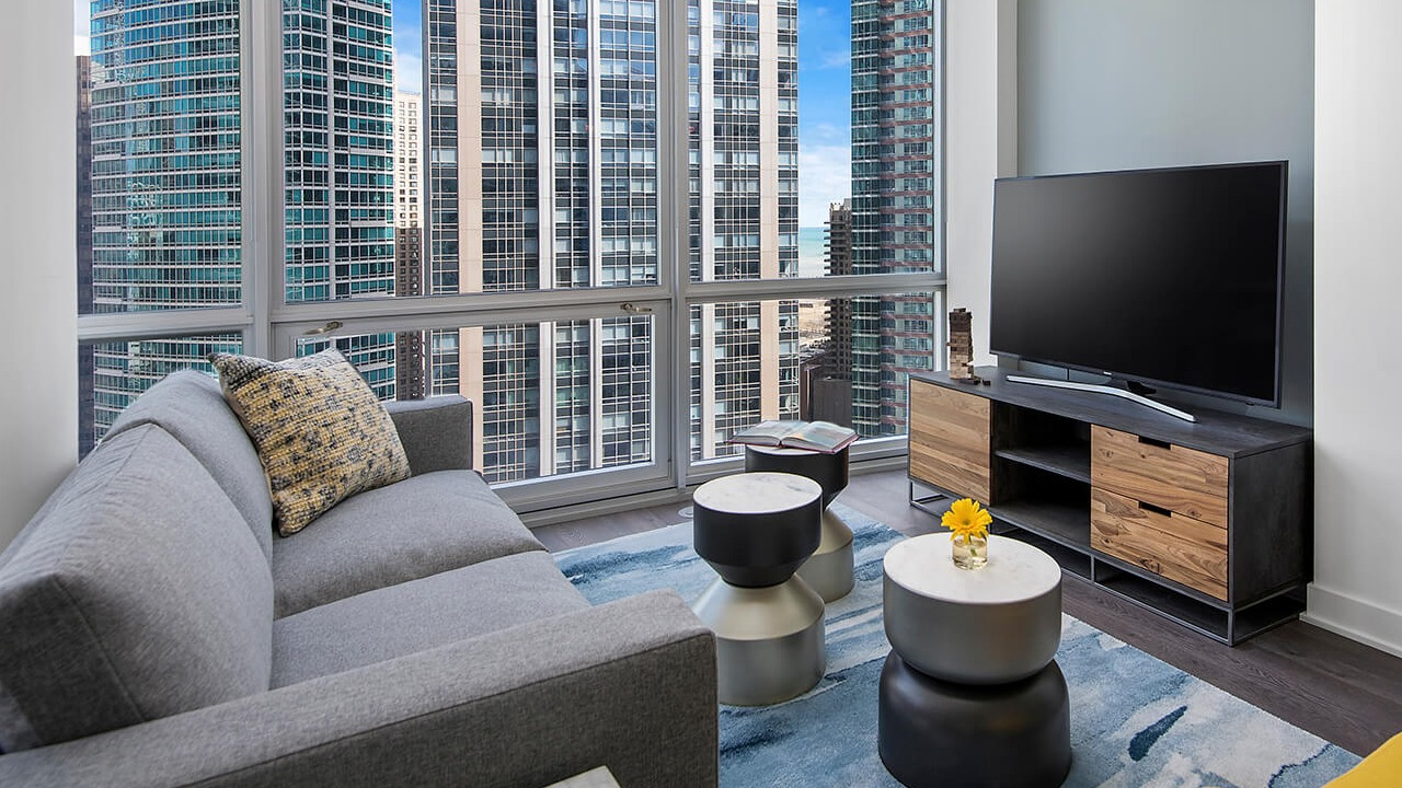 Living room with modern sofa, TV setup, and skyline views at 465 North Park apartments in Chicago
