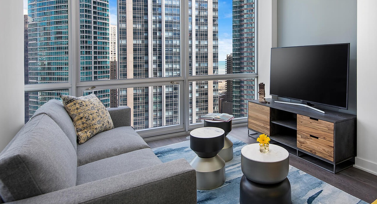 Living room with modern sofa, TV setup, and skyline views at 465 North Park apartments in Chicago