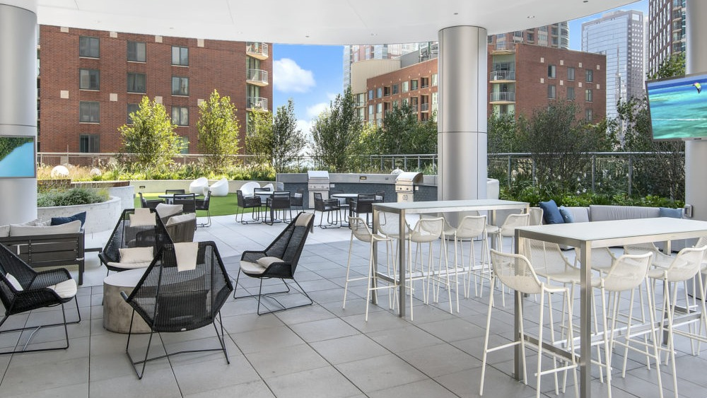 Covered outdoor lounge with dining tables and modern seating at 465 North Park apartments in Chicago