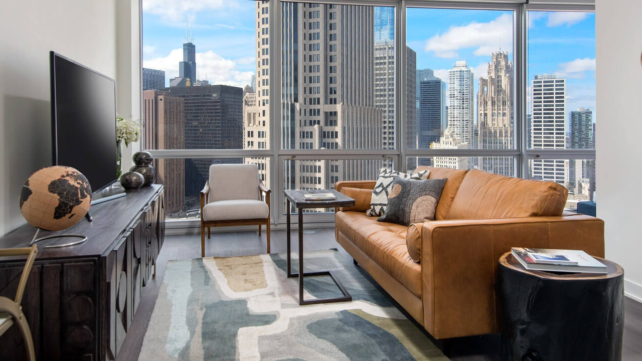 Cozy living room with leather sofa, modern rug, and skyline backdrop at 465 North Park apartments in Chicago