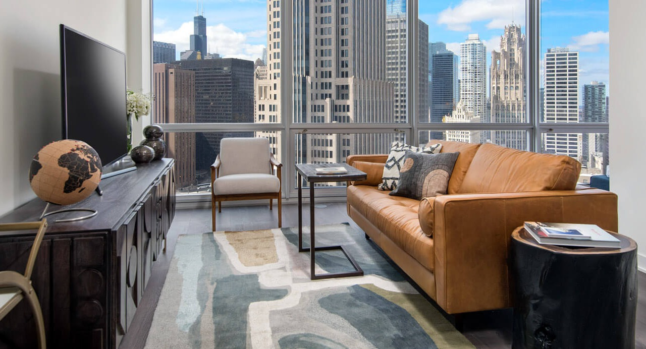 Cozy living room with leather sofa, modern rug, and skyline backdrop at 465 North Park apartments in Chicago