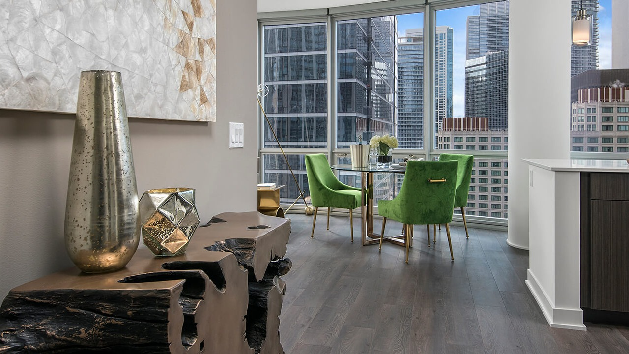 Dining area with green velvet chairs, modern décor, and floor-to-ceiling windows at 465 North Park apartments in Chicago