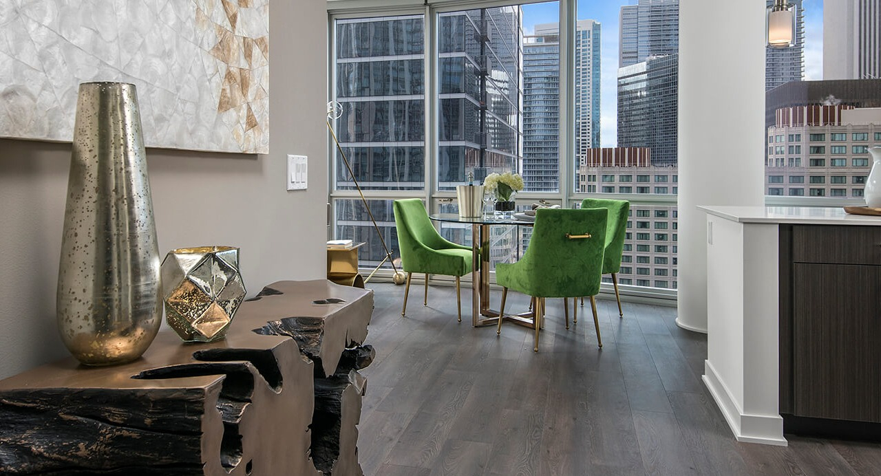 Dining area with green velvet chairs, modern décor, and floor-to-ceiling windows at 465 North Park apartments in Chicago