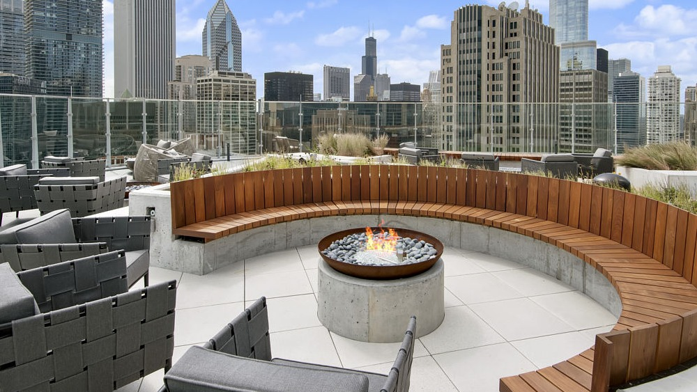 Circular firepit lounge with wood seating and skyline backdrop at 465 North Park apartments in Chicago