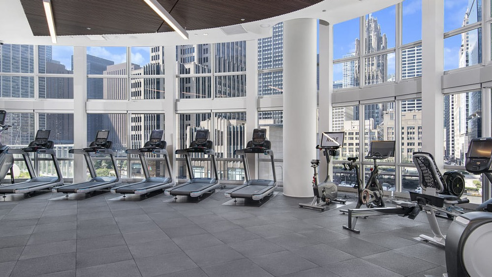 Bright fitness center with treadmills, bikes, and skyline views at 465 North Park apartments in Chicago