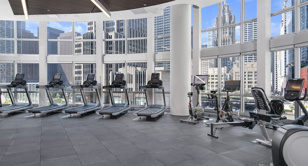 Bright fitness center with treadmills, bikes, and skyline views at 465 North Park apartments in Chicago