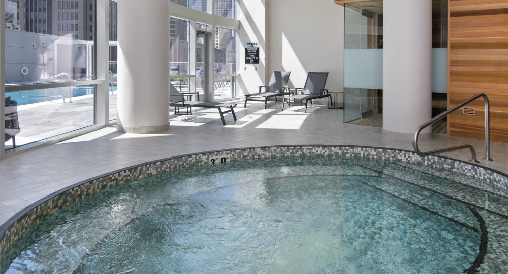 Indoor spa with whirlpool, sauna, and poolside seating at 465 North Park apartments in Chicago