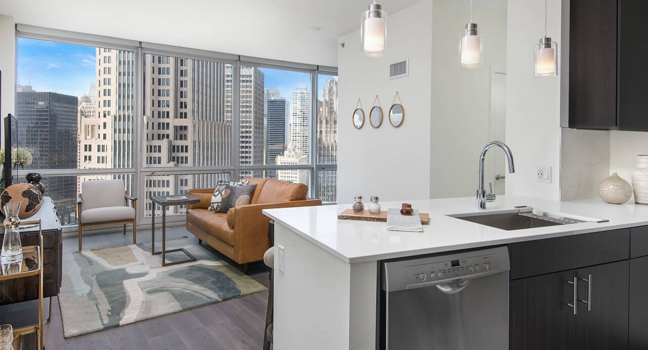 Kitchen and living room with modern finishes, pendant lighting, and skyline views at 465 North Park apartments in Chicago
