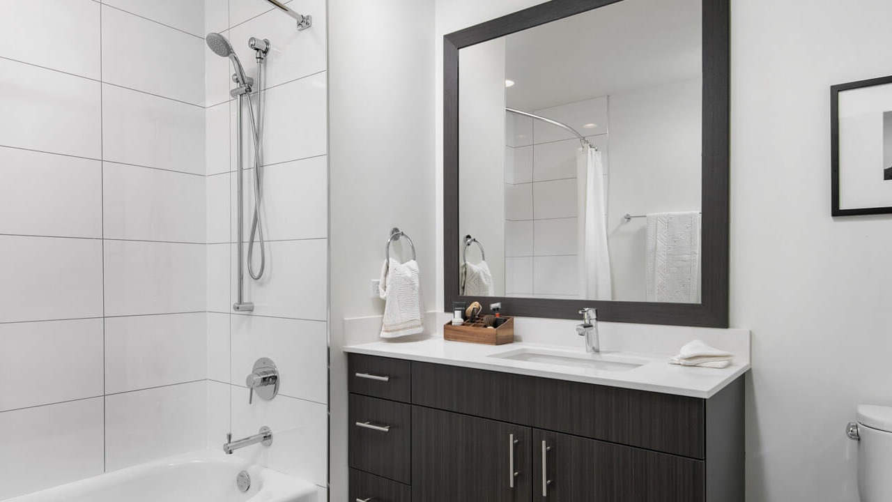 Modern bathroom with white tiles, sleek vanity, and bathtub at 465 North Park apartments in Chicago