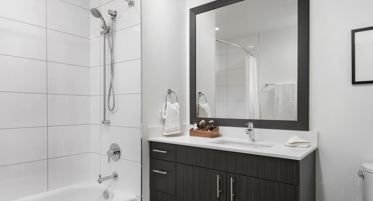 Modern bathroom with white tiles, sleek vanity, and bathtub at 465 North Park apartments in Chicago