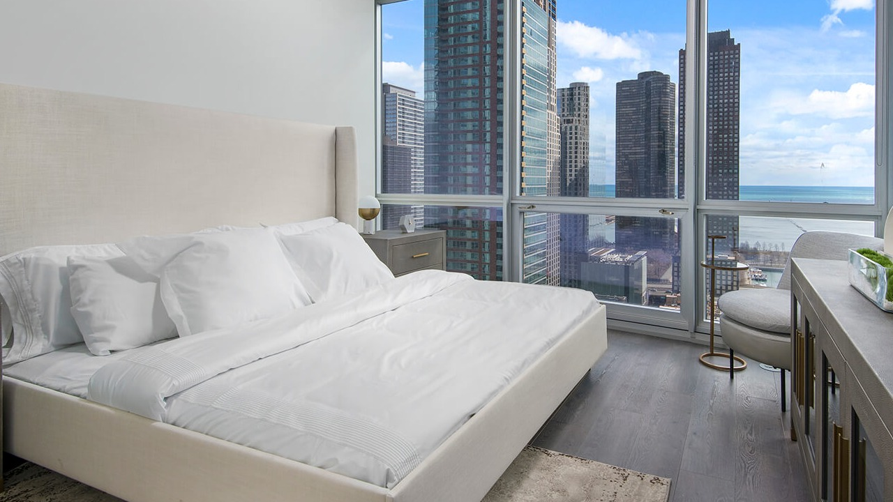 Modern bedroom with large windows, city and lake views, and natural light at 465 North Park apartments in Chicago