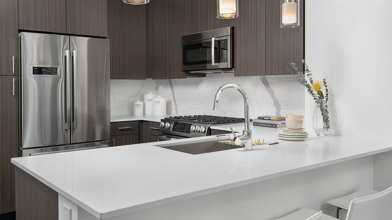 Modern kitchen with quartz island, pendant lighting, and dark cabinetry at 465 North Park apartments in Chicago