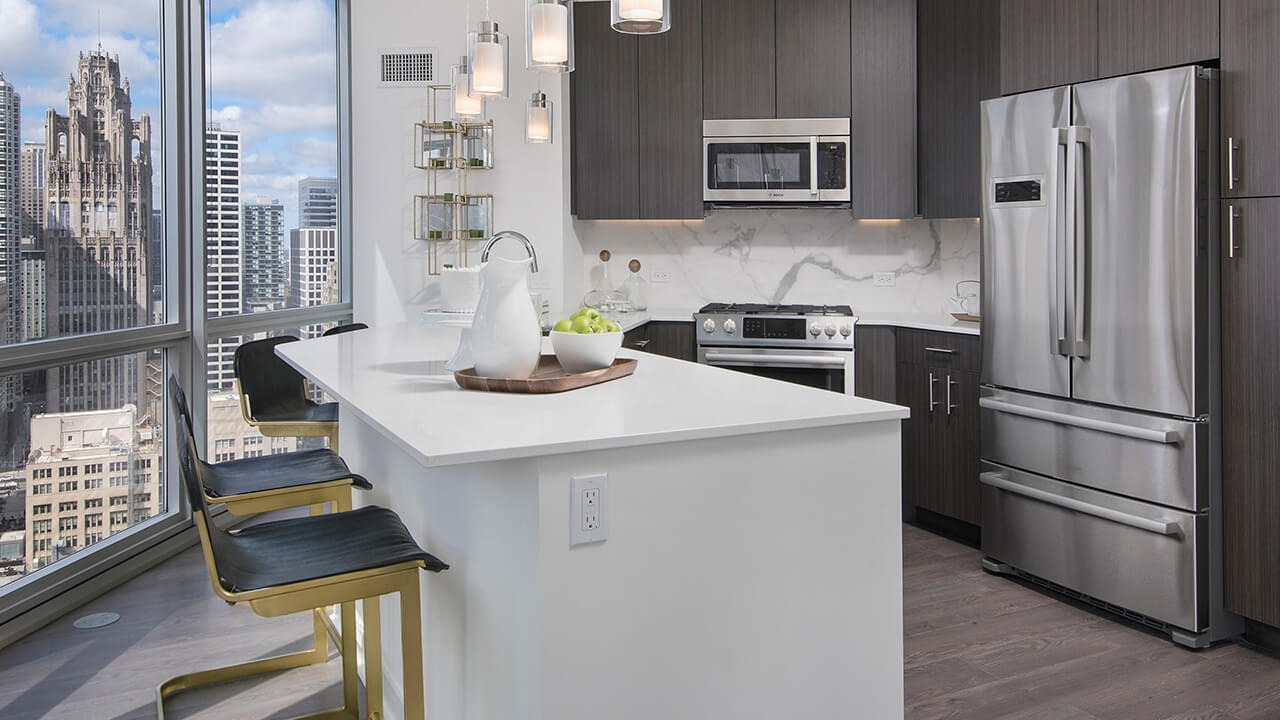 Modern kitchen with stainless steel appliances, pendant lighting, and city views at 465 North Park apartments in Chicago