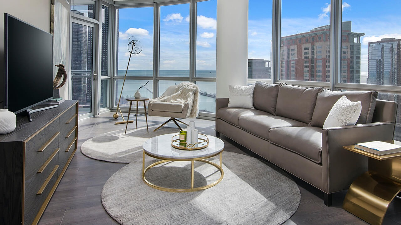 Modern living room with leather sofa, large windows, and lake views at 465 North Park apartments in Chicago
