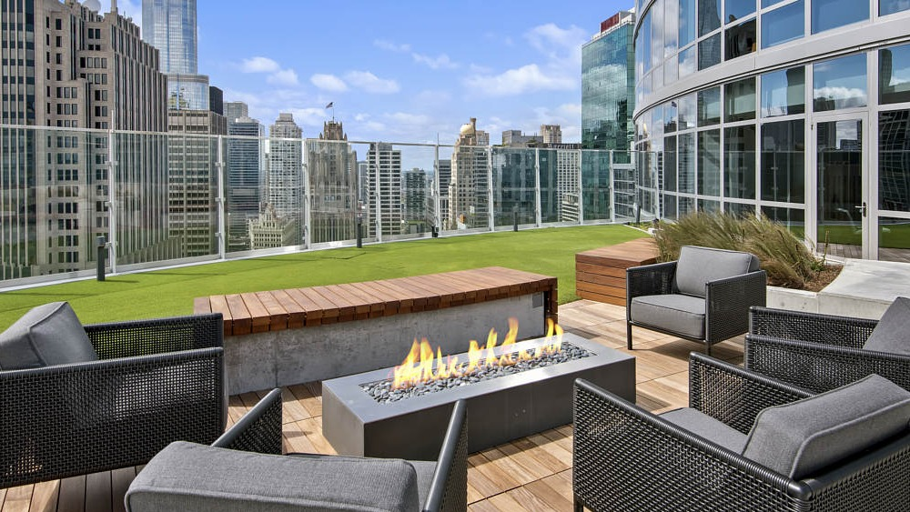 Rooftop lounge with modern fireplace, seating, and city skyline views at 465 North Park apartments in Chicago