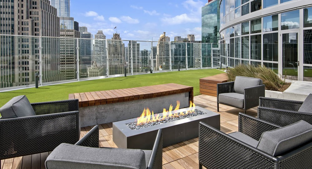 Rooftop lounge with modern fireplace, seating, and city skyline views at 465 North Park apartments in Chicago
