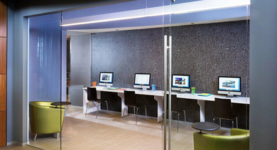 Glass-enclosed resident business center with iMac workstations, modern seating, and accent wall design at 500 Lake Shore Drive luxury apartments in Chicago