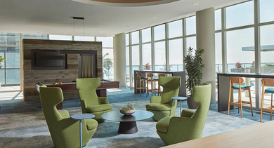 Bright resident clubroom featuring green lounge chairs, social seating, a pool table, and bar stools with pool and lake views at 500 Lake Shore Drive in Chicago