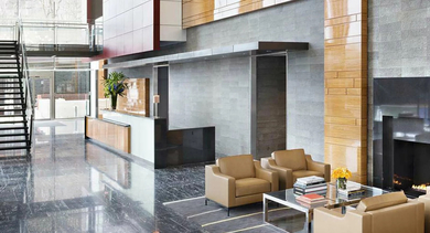 Sophisticated two-story lobby with marble floors, modern fireplace, seating areas, and statement lighting at 500 Lake Shore Drive luxury apartments in Chicago