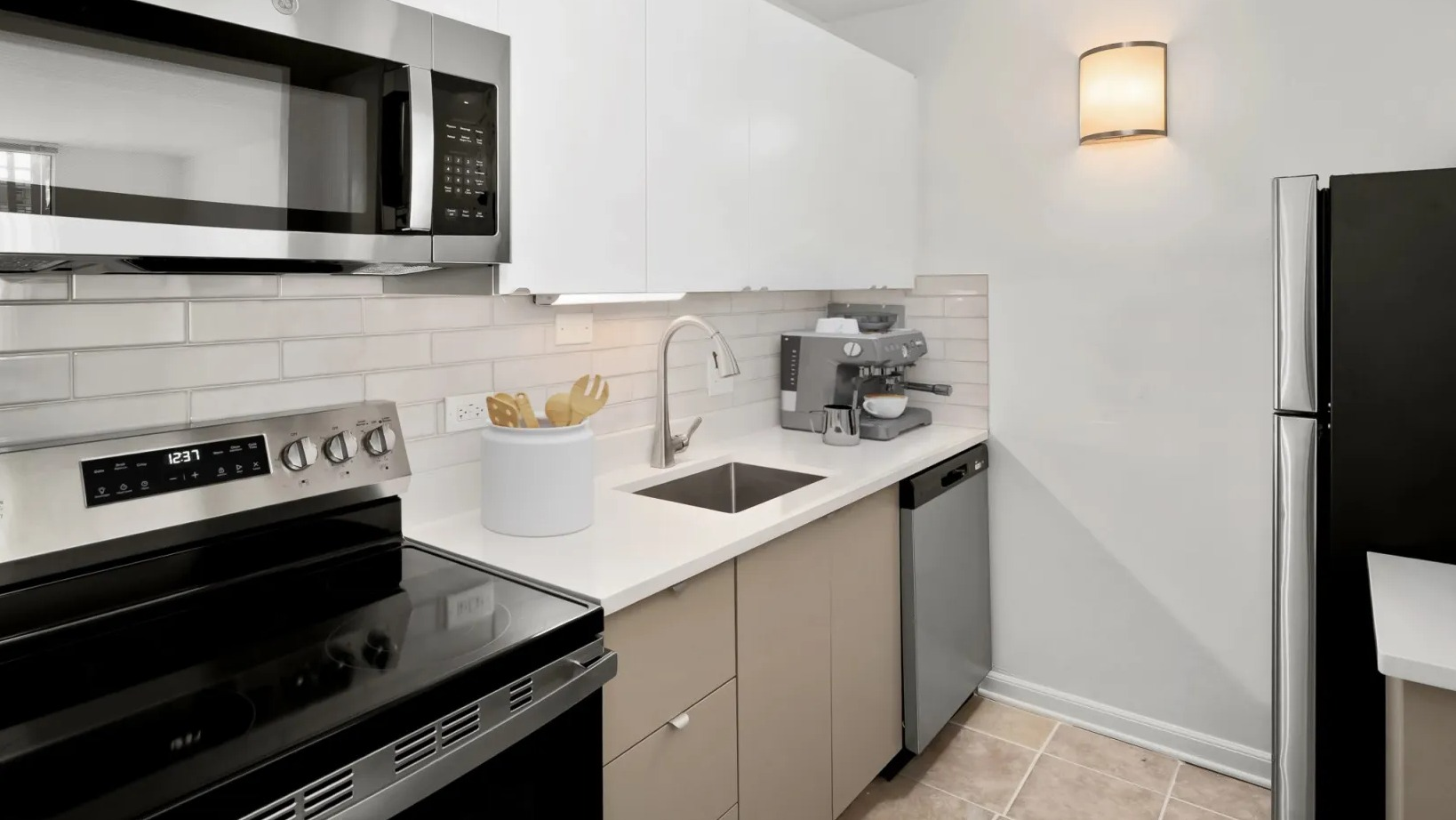 Sleek galley kitchen with white upper cabinets, subway tile backsplash, stainless appliances, and quartz counters at 55 West Chestnut apartments in Chicago
