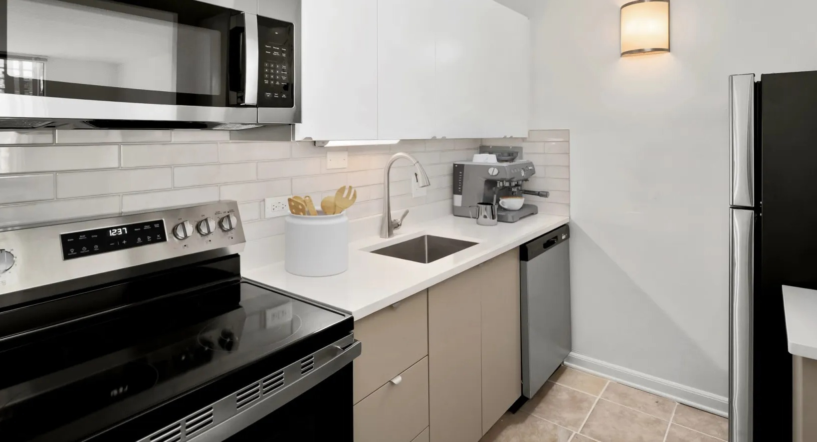 Sleek galley kitchen with white upper cabinets, subway tile backsplash, stainless appliances, and quartz counters at 55 West Chestnut apartments in Chicago