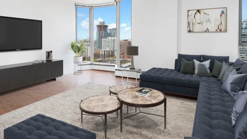 Spacious living room with tufted navy sectional, round marble coffee tables, and skyline views at 55 West Chestnut apartments in Chicago