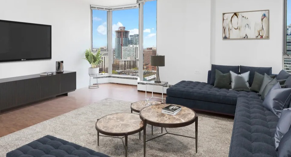 Spacious living room with tufted navy sectional, round marble coffee tables, and skyline views at 55 West Chestnut apartments in Chicago