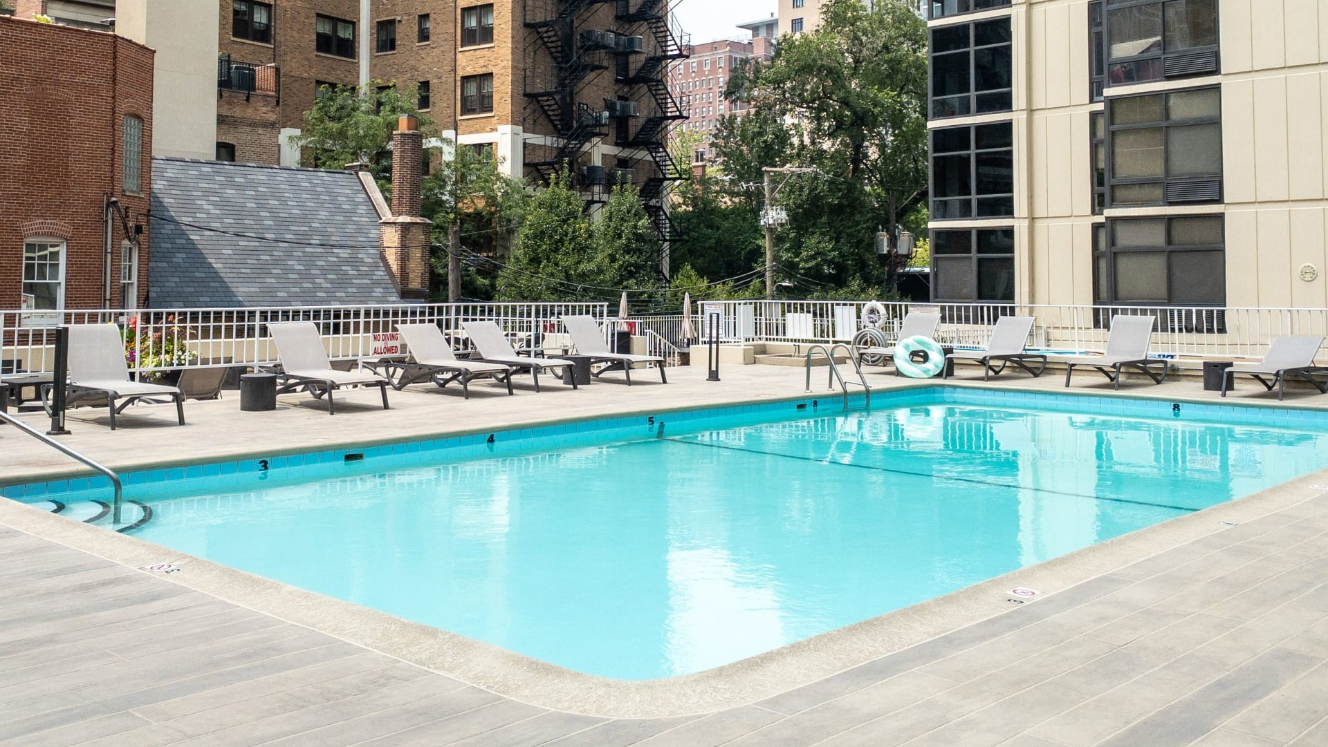 Outdoor swimming pool with lounge chairs and city backdrop on the resident sundeck at 65 East Scott apartments in Chicago