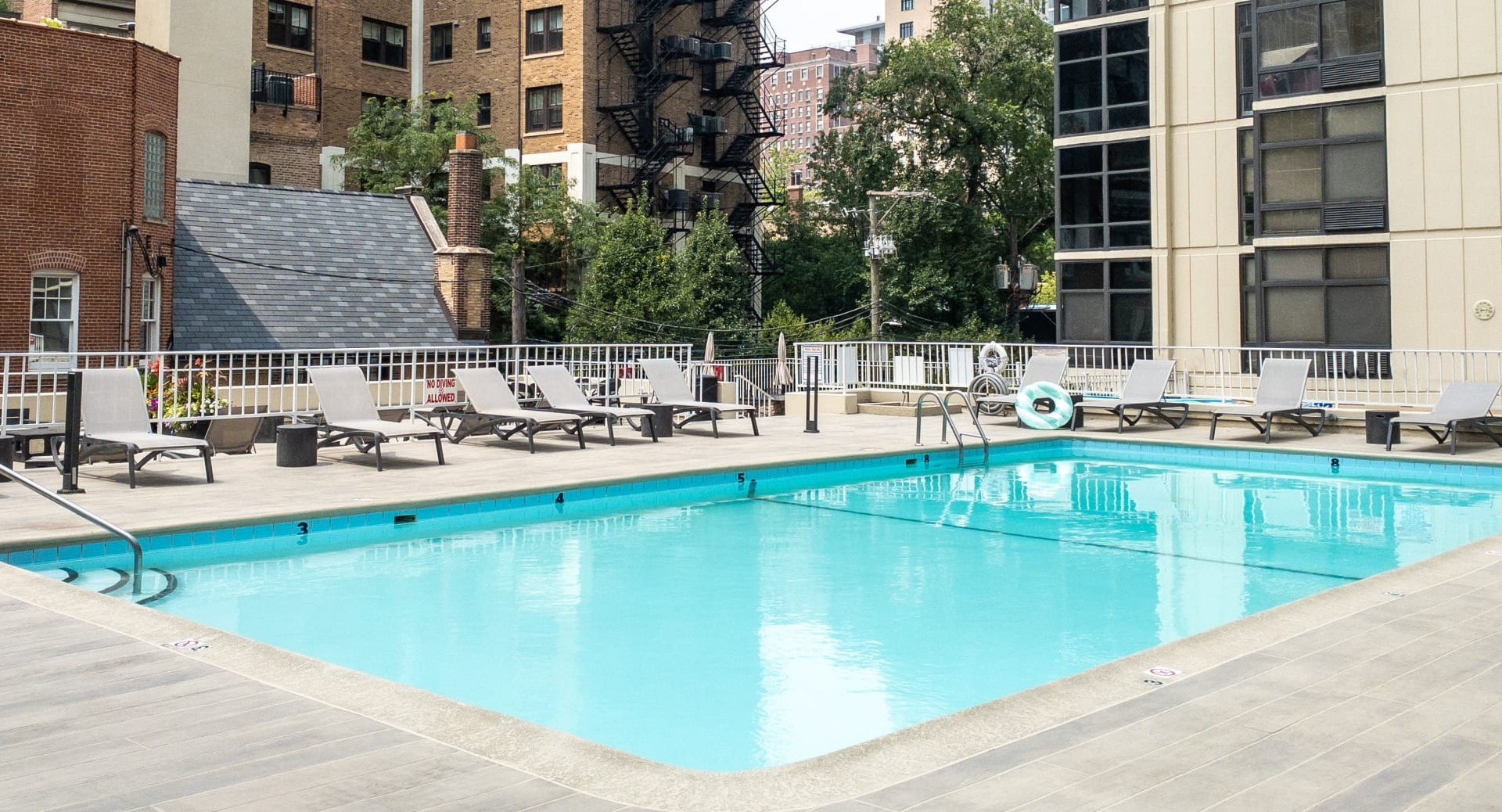 Outdoor swimming pool with lounge chairs and city backdrop on the resident sundeck at 65 East Scott apartments in Chicago