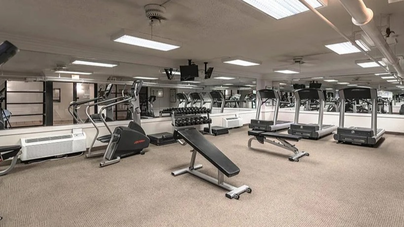 Apartment gym with multiple treadmills, ellipticals, mirrors, and strength equipment at 65 East Scott apartments in Chicago