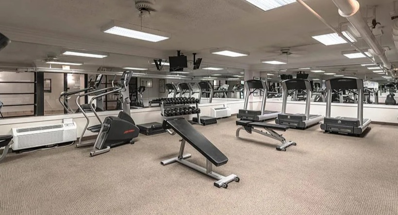 Apartment gym with multiple treadmills, ellipticals, mirrors, and strength equipment at 65 East Scott apartments in Chicago
