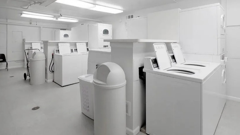 On-site laundry room with multiple washers, dryers, folding table, and bright lighting at 65 East Scott apartments in Chicago