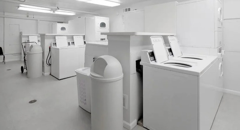 On-site laundry room with multiple washers, dryers, folding table, and bright lighting at 65 East Scott apartments in Chicago